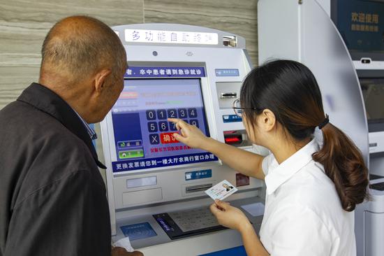 服務(wù)人員通過(guò)掛號(hào)自助機(jī)為老人預(yù)約專(zhuān)家。潘迎霞 攝